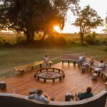 The Camp fire is set up in the centre of the seating area on a wooden deck with gorgeous views of the surroundings at Camp Moremi