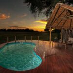 The pristine wooden pool deck at Chitabe Camp lit up by an African sunset
