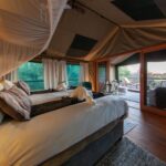 Luxurious tented bedroom with mosquito netting and private deck at Mma Dinare Camp.