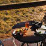 Guest enjoying breakfast and tea on a wooden deck overlooking the Okavango Delta.