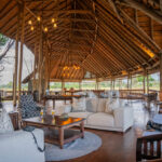 Spacious open-air lounge with thatched roof and sofas at Moremi Crossing.