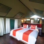 Interior of a safari tent with twin beds and wooden floors at Moremi Crossing in Botswana.