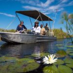 Little Vumbura fishing boat glides through the waterlilies
