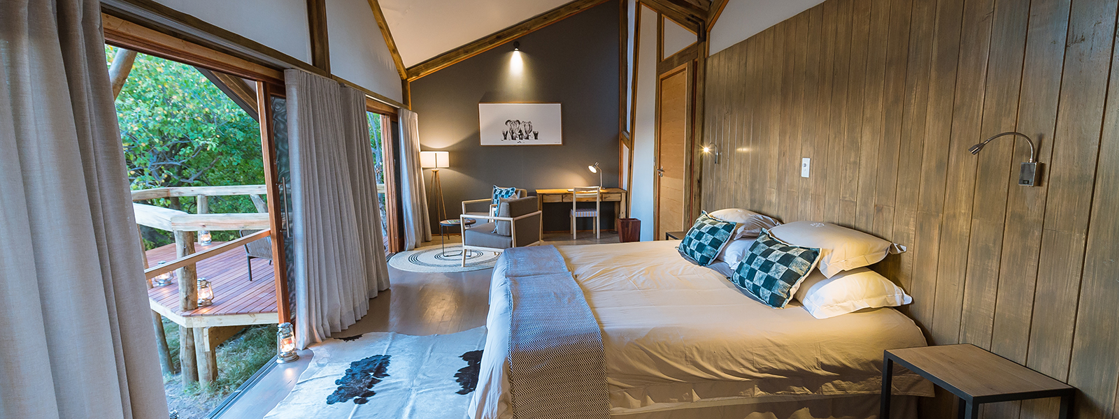 Spacious bedroom with a king-sized bed and wooden deck views at Splash Camp.