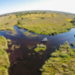 Aerial view of boat cruising through Okavango Delta channels near Kwara Camp.