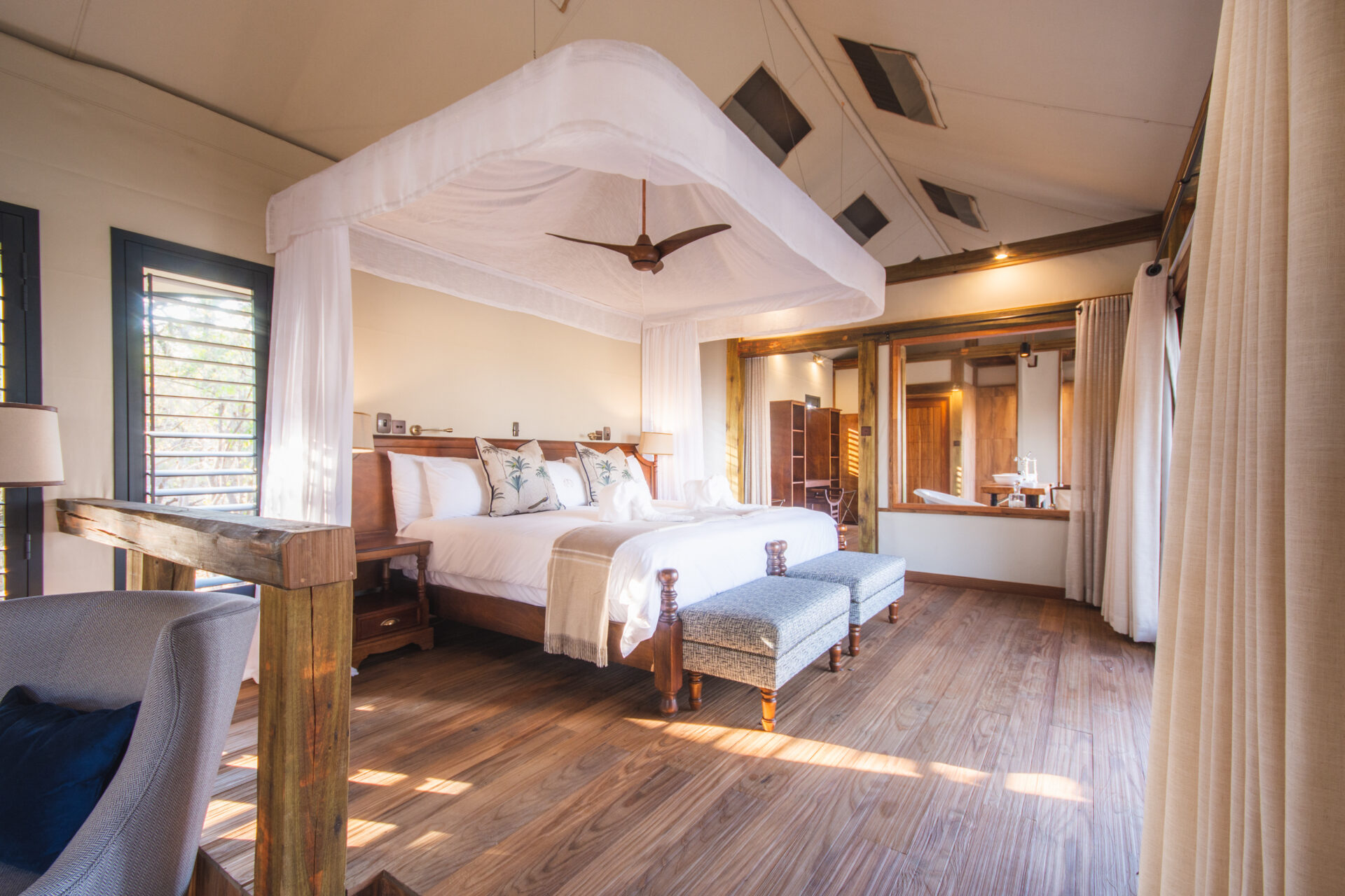 Luxury safari tent suite with canopy bed and open bathroom at Kwara Camp.