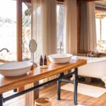 Open-plan safari bathroom with clawfoot tub and double sinks at Kwara Camp.