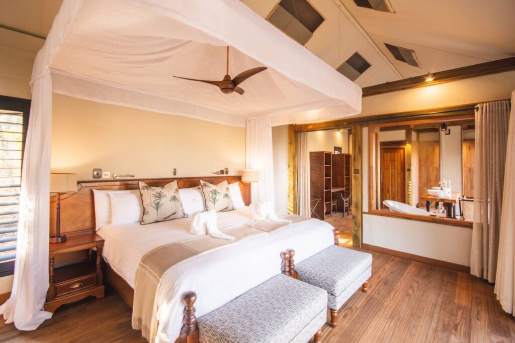 Luxury safari tent suite with canopy bed and open bathroom at Kwara Camp.