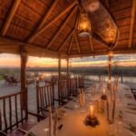Dining room and outside fire pit at Camp Xakanaxa against sunset
