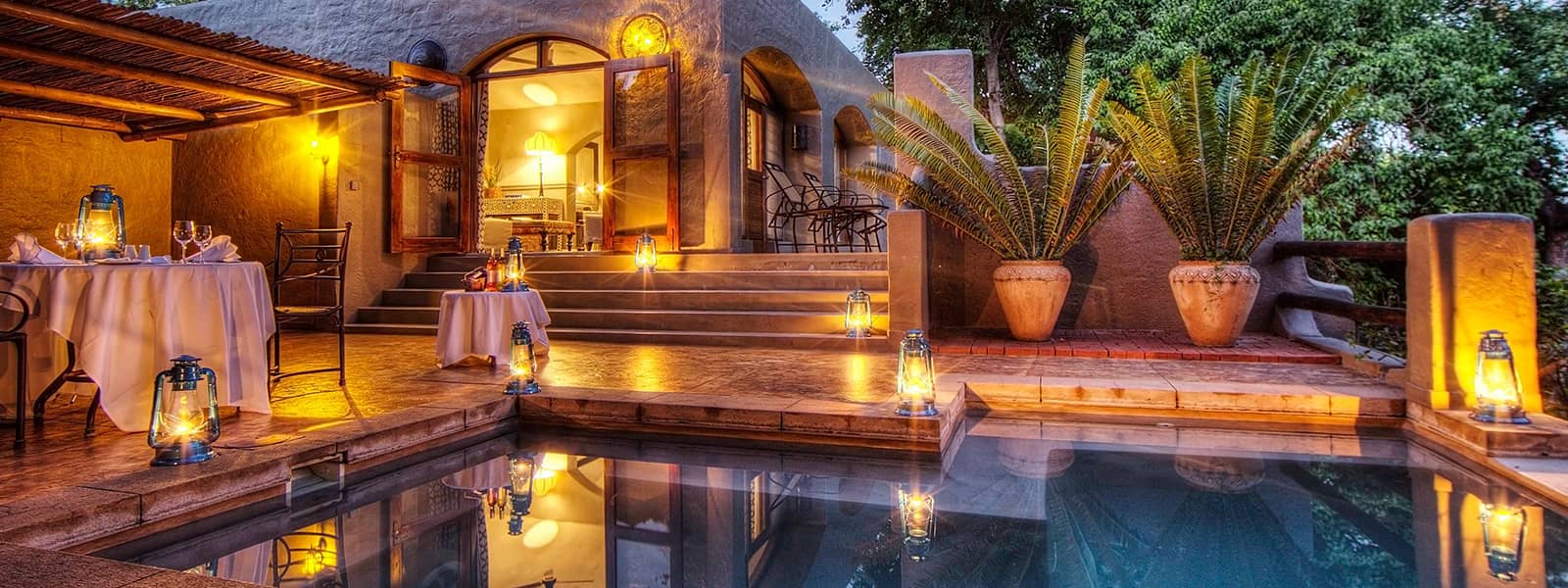 Private dinner tables set around the pool at Chobe Game Lodge