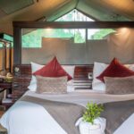 Safari tent bedroom with double bed and warm lighting at Pom Pom Camp.