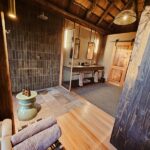 Modern en-suite bathroom at Kanana Camp with natural finishes and earthy colours inspired by the Okavango landscape.