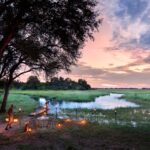 Candlelit riverside dinner setup at Linyanti Leadwood in Botswana.