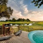 Linyanti Leadwood pool deck with cocktail setup and scenic floodplain view in Botswana.