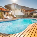 Curved swimming pool with loungers and thatched main area at Tau Pan Camp.