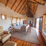 Thatched chalet bedroom with king-sized bed and panoramic views at Tau Pan Camp.