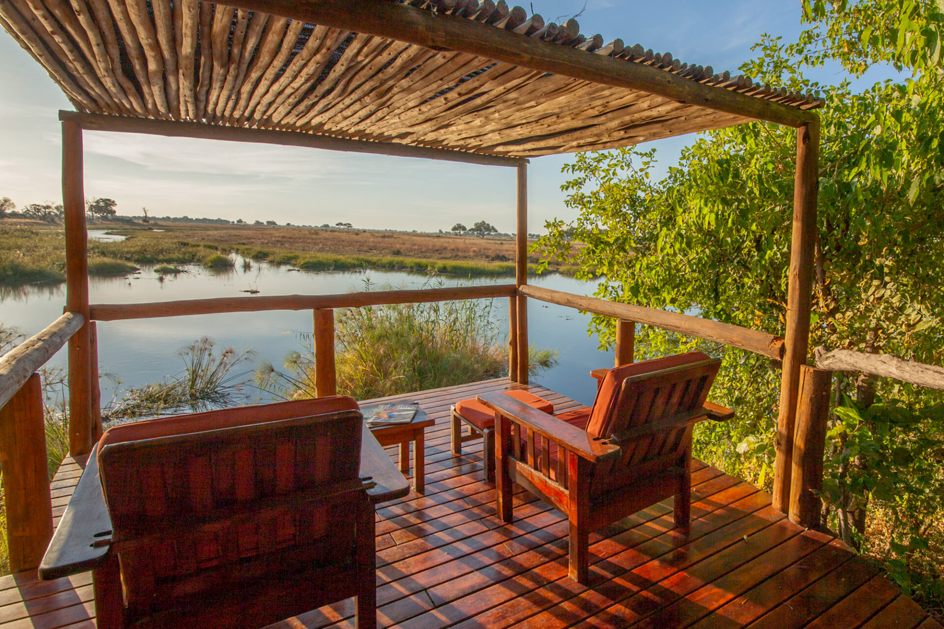 Two wooden chairs on a shaded deck overlooking the lagoon and open plains.