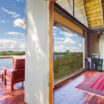 Open safari tent suite with wooden floors and view of lagoon from private deck.