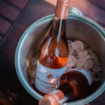 Two bottles of rosé wine in an ice bucket on a wooden table.