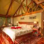Spacious tented bedroom with a large bed, wooden floors, and natural light at Lebala Camp.
