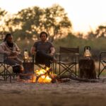 Camp fire drinks and sunset with guests from Machaba Camp