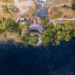 Aerial view of Pom Pom Camp beside a blue lagoon in the Okavango Delta.