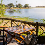 Wooden deck table with chairs overlooking the lagoon at Pom Pom Camp.