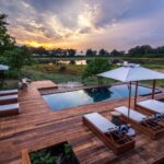 Wooden deck area boasting sparkling pool and sun loungers at Qorokwe
