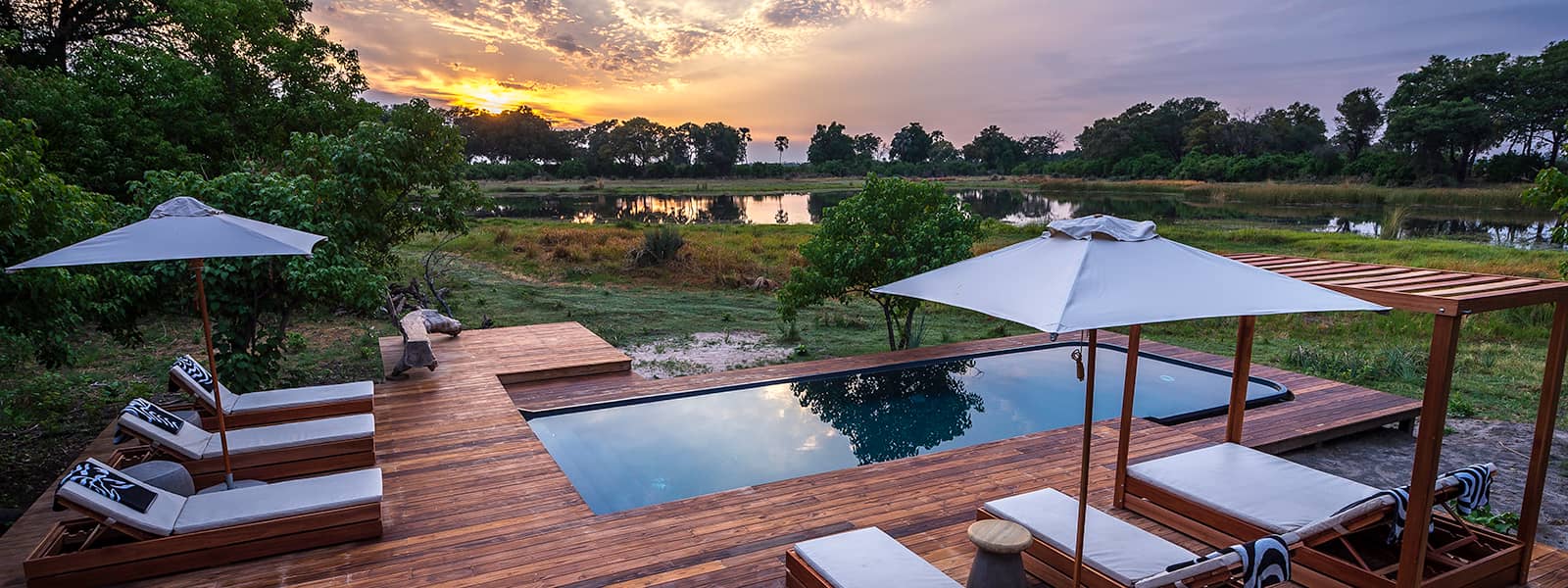 Wooden deck area boasting sparkling pool and sun loungers at Qorokwe