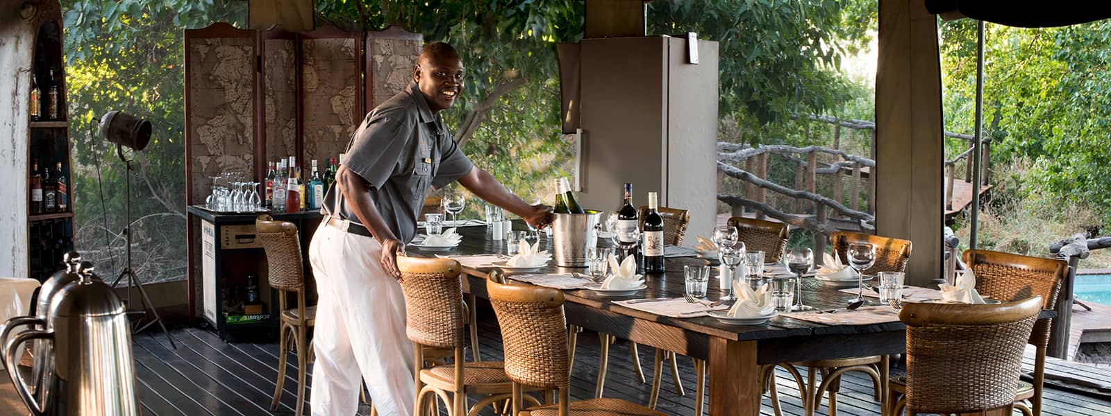 Khwai Ebony Camp open-air dining area with staff setting table in Botswana.