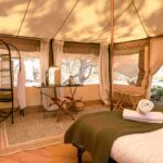 Spacious walk-in safari tent with bed and furnishings at a remote riding safari camp.