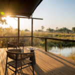 Wooden deck with chairs overlooking a water channel at Four Rivers Camp.