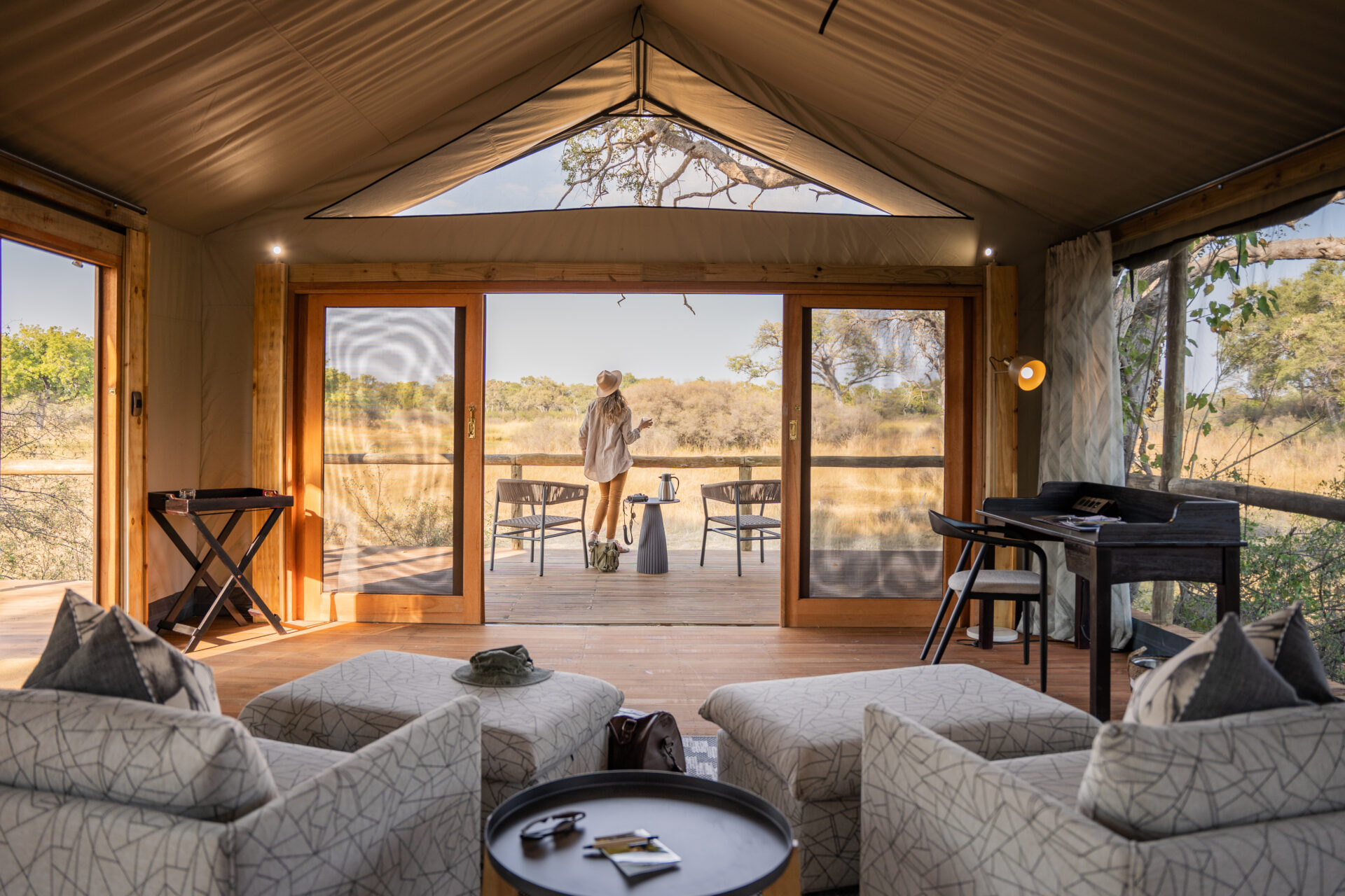 Interior of tented lounge with sofas and glass doors overlooking the Okavango Delta.