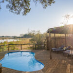Swimming pool and loungers on a wooden deck overlooking wetlands at Four Rivers Camp.