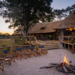Firepit area with chairs in front of main lodge at dusk at Four Rivers Camp.