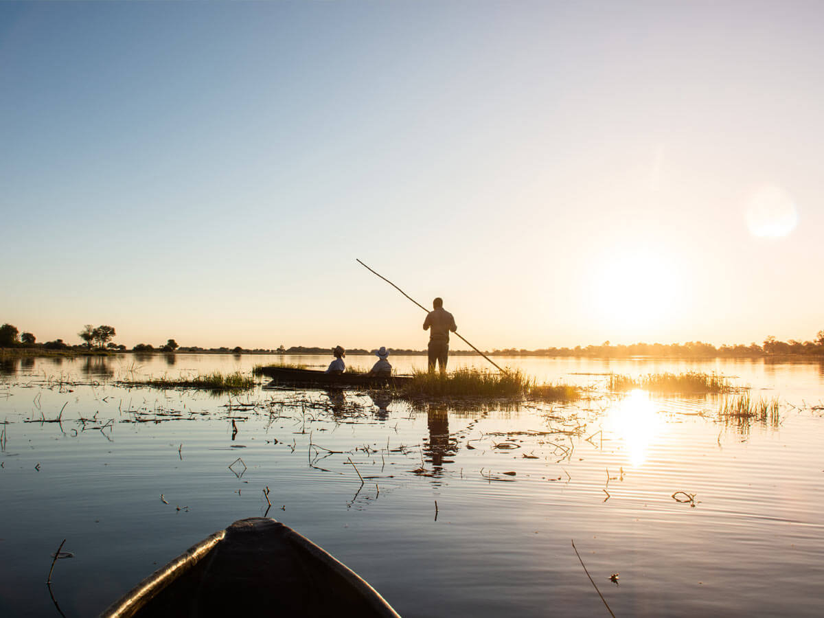 Mokoro canoe on calm water at sunset near Four Rivers Camp.