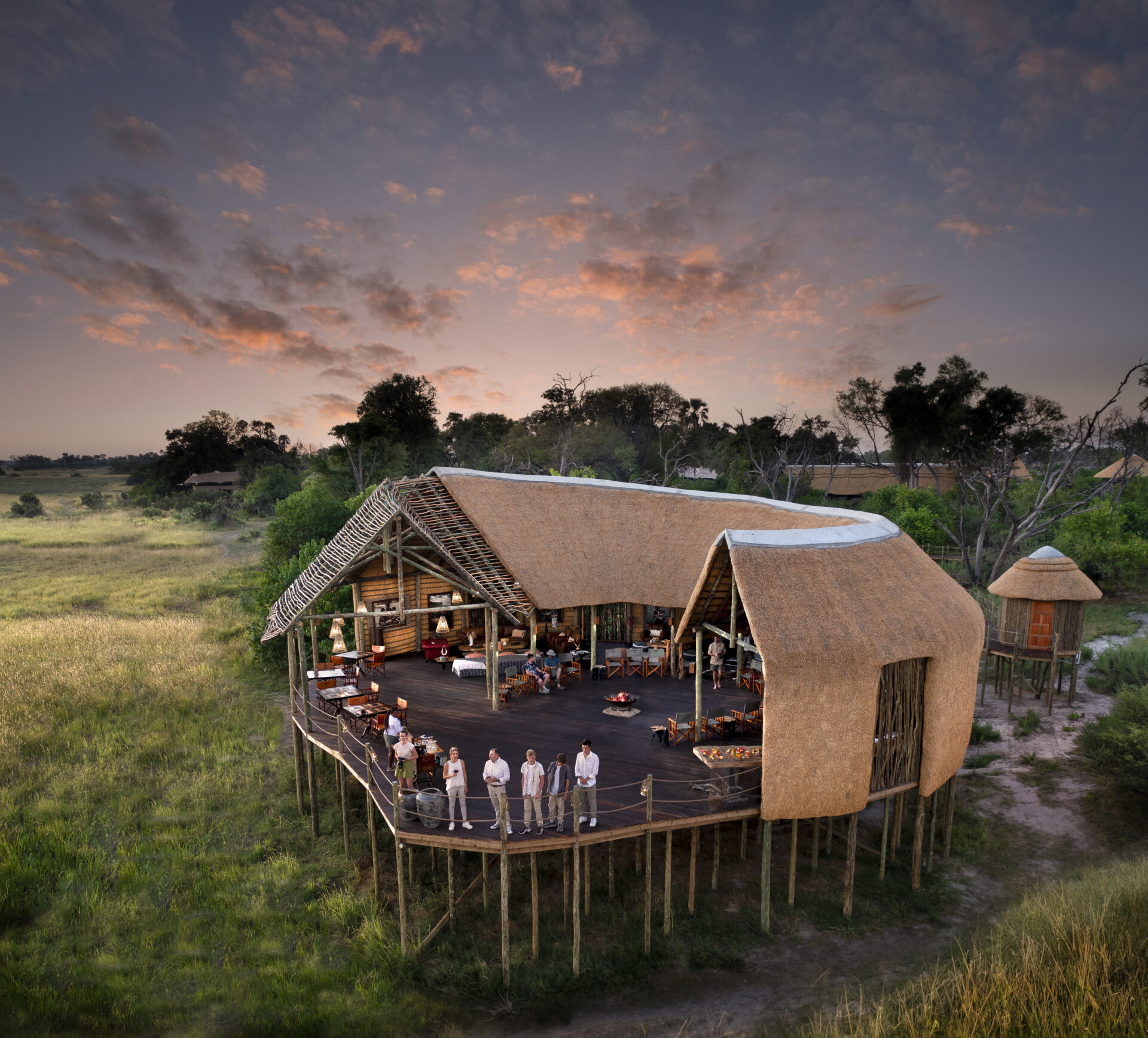Atzaró Okavango Camp main lodge with guests on elevated deck in Botswana.