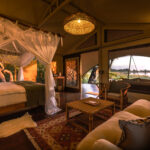 Elegant safari-style bedroom at Maxa in Botswana with a king bed, natural wood accents, and woven décor