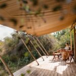 A lady relaxed on her private deck, with a table and chair outside her tented room