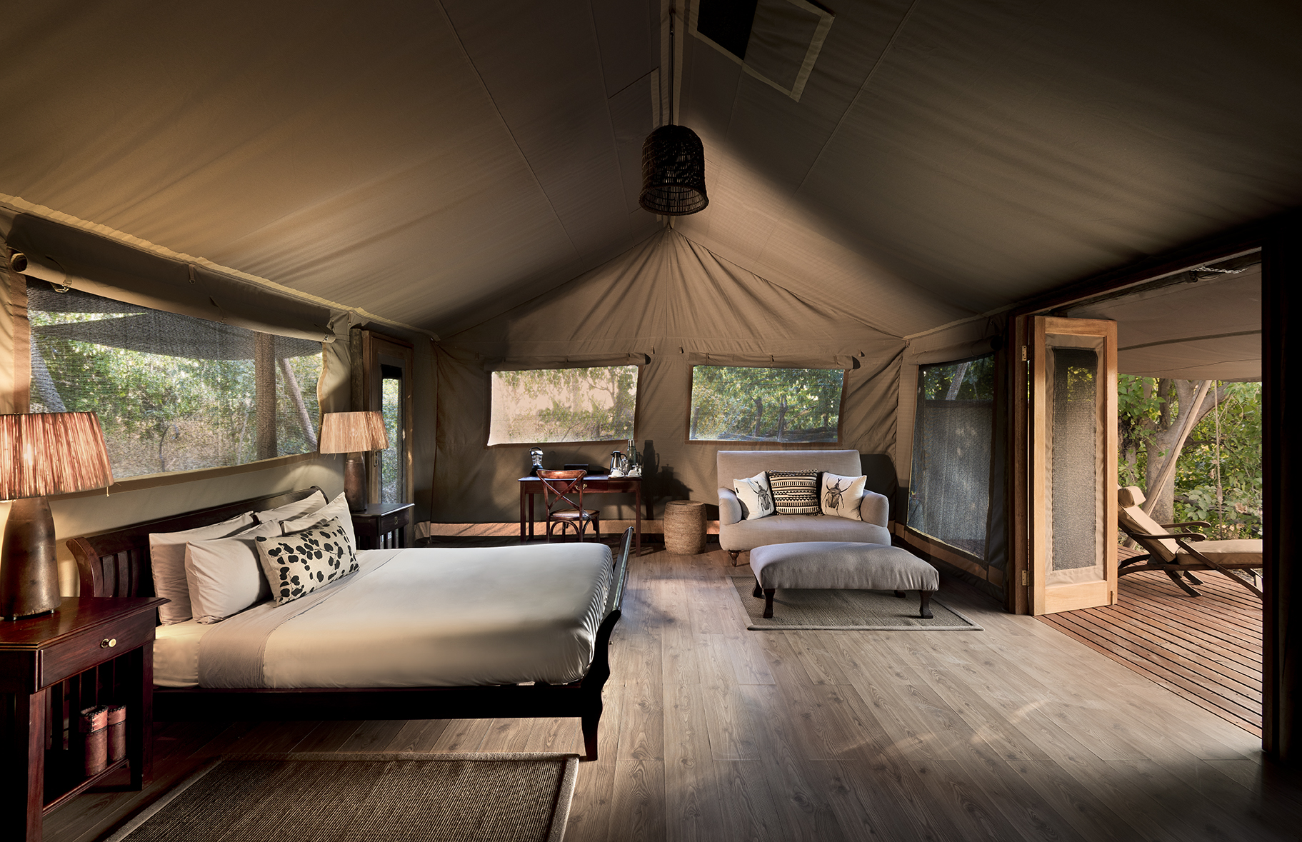 Interior of luxury tent with bed, sofa, and writing desk at Linyanti Bush Camp in Botswana.