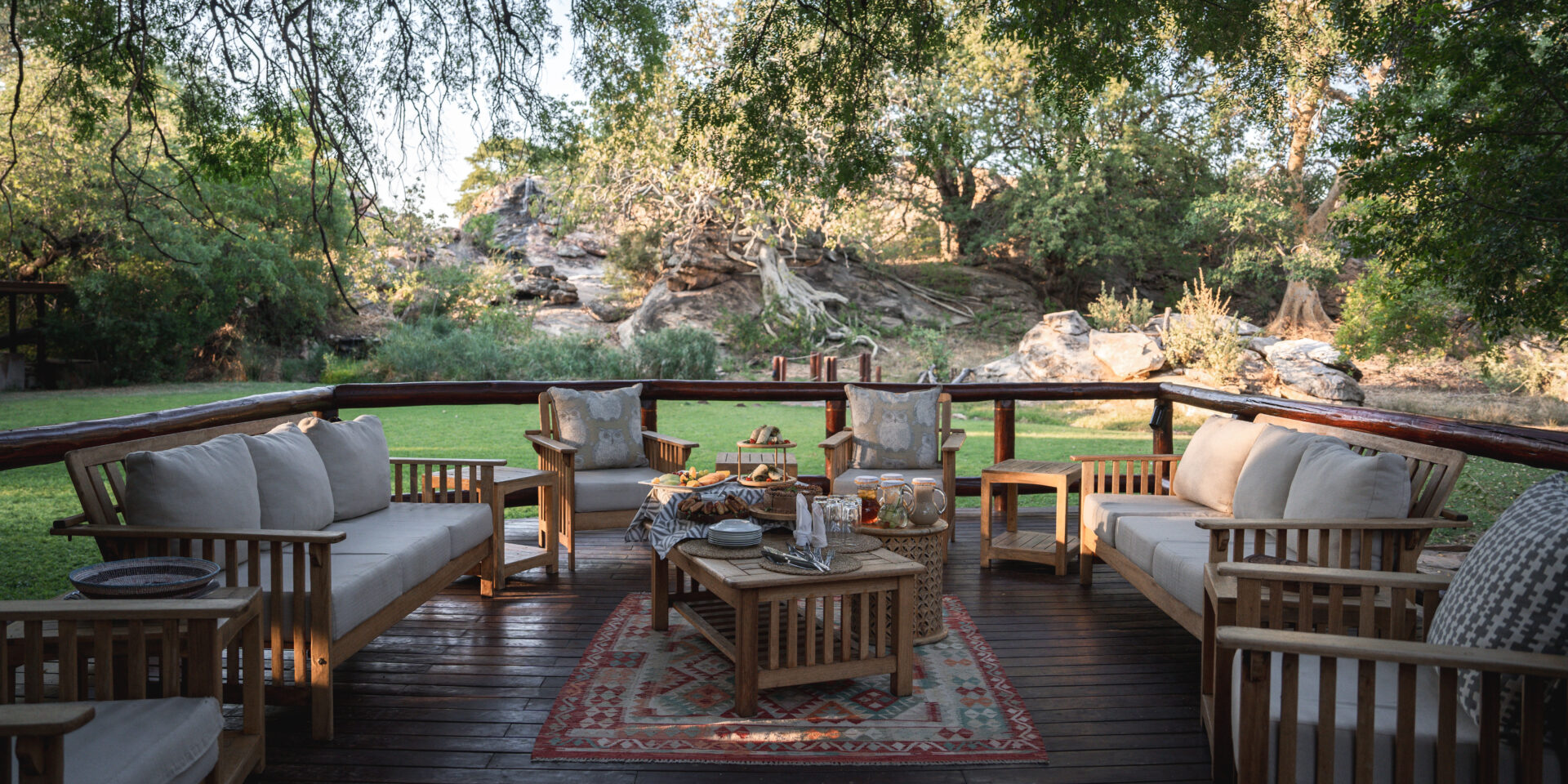 Raised main area shaded by a forest of trees at Tuli Safari Lodge Mashatu over looking lush green lawn