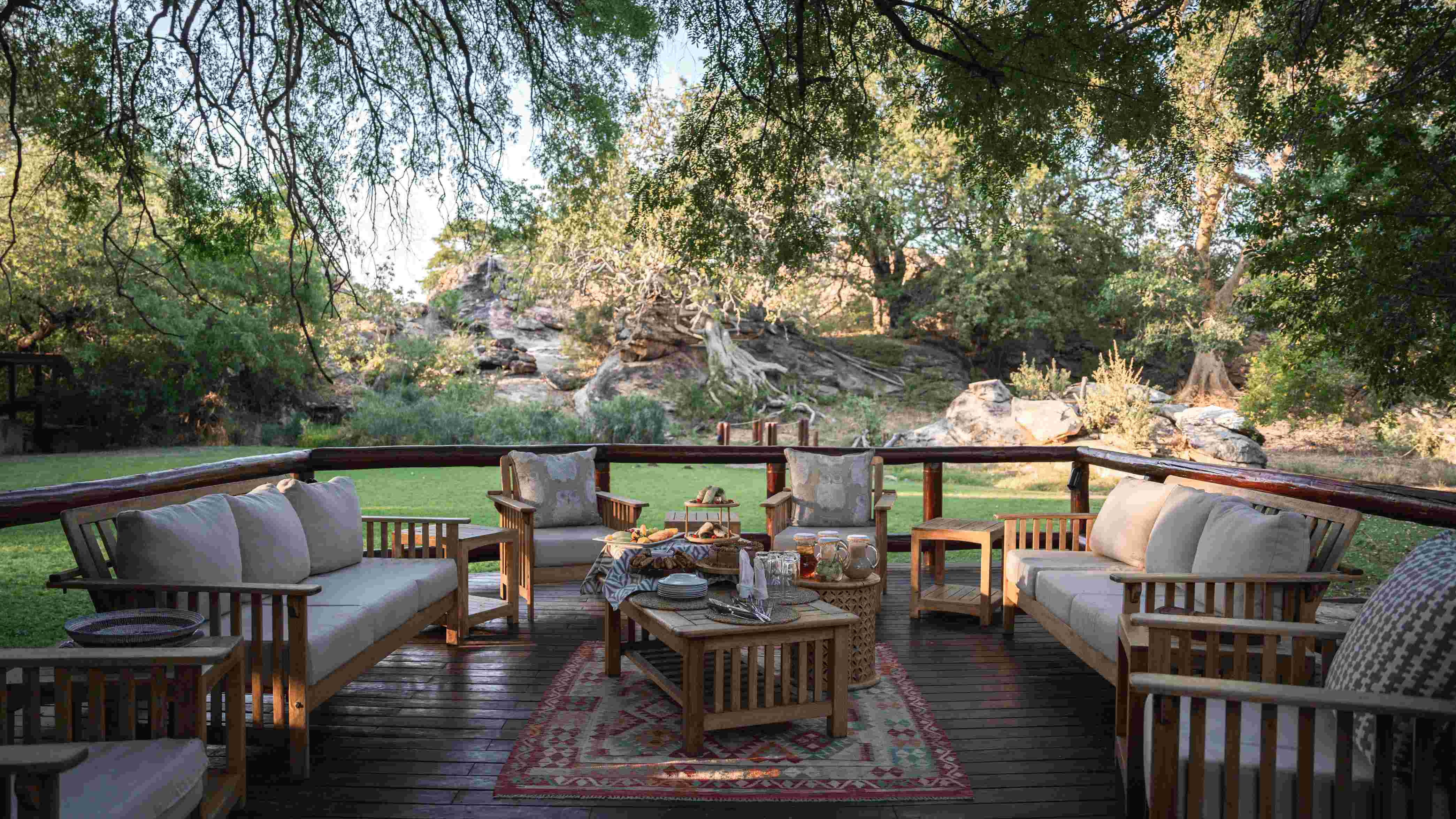 Raised main area shaded by a forest of trees at Tuli Safari Lodge Mashatu over looking lush green lawn