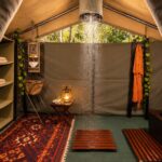 Canvas safari tent en-suite bathroom featuring an open-air bucket shower and traditional furnishings.