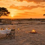 Outdoor safari dinner table at Harkness safaris and campfire set up in Savute, Botswana,at sunset.